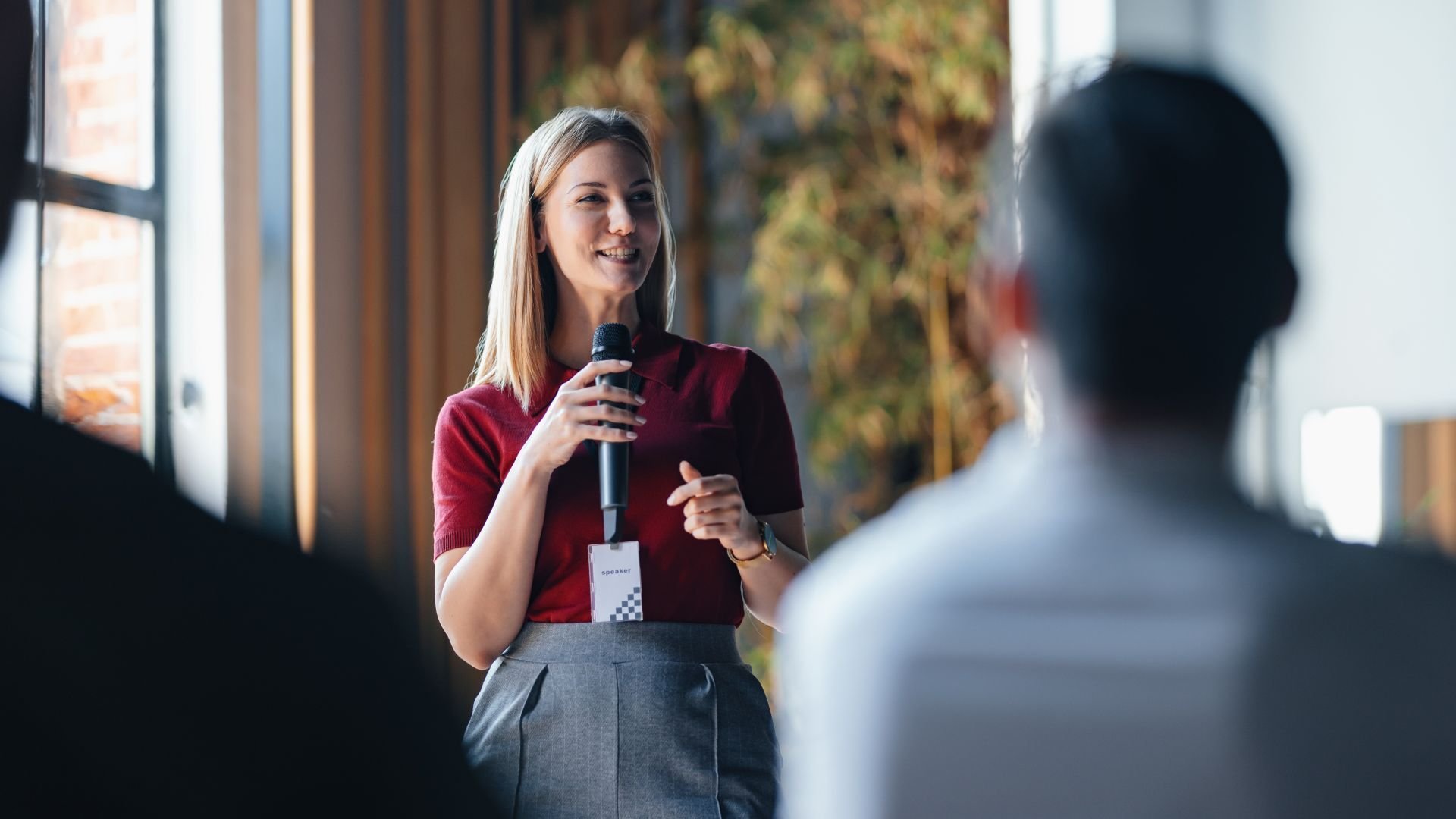 Woman giving a talk through a microphone in front of others