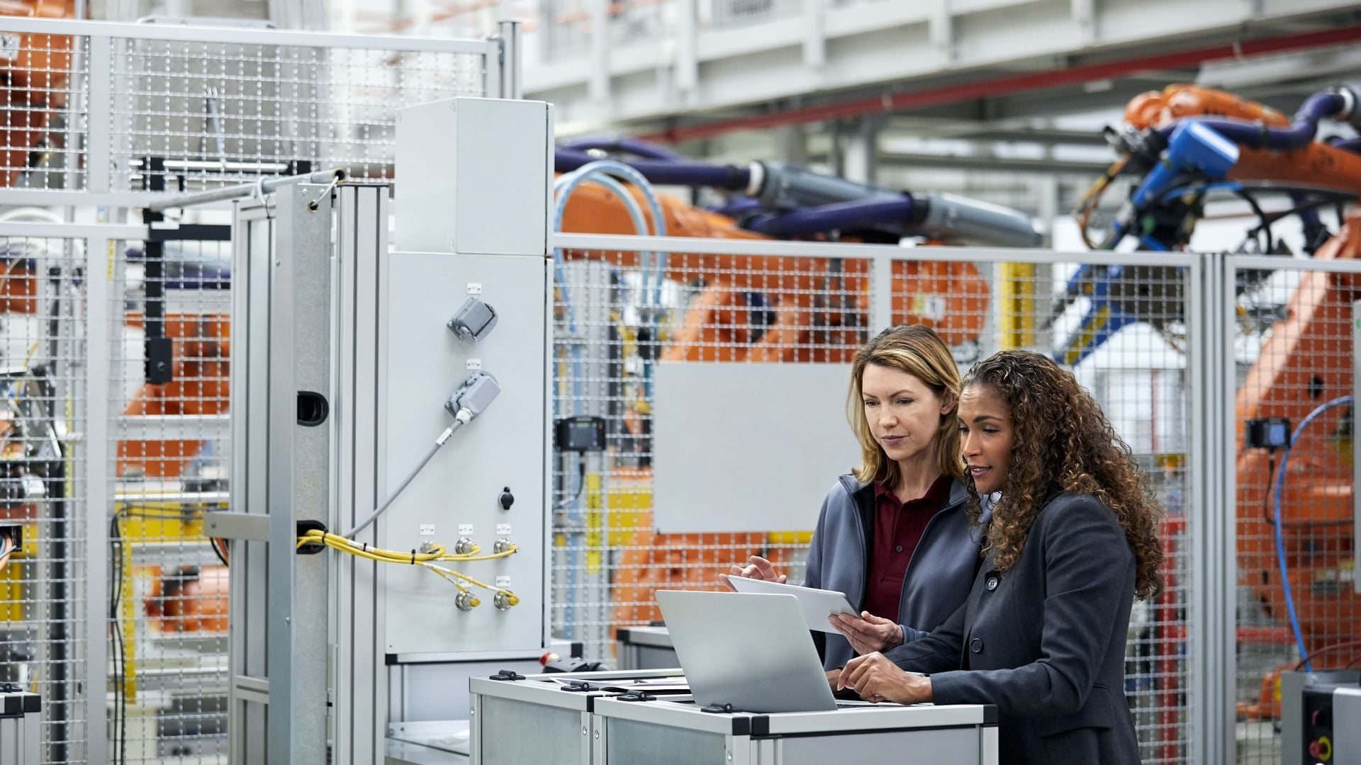 Two people working on laptop in industrial factory setting