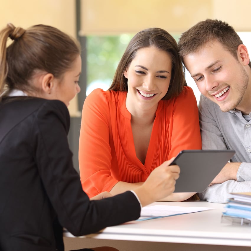 A young couple being advised and shown an ipad by a woman.