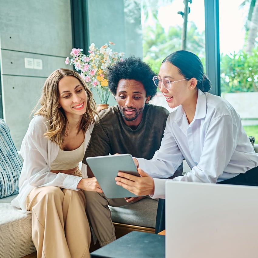 3 people all looking at a tablet and smiling