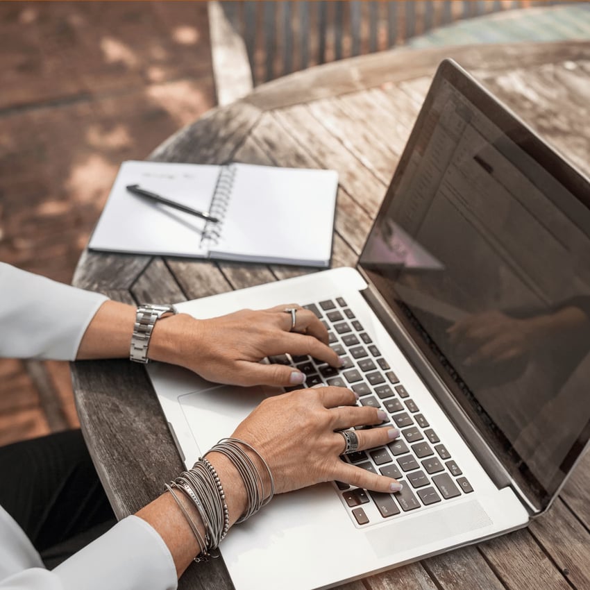 a women outside typing on a laptop