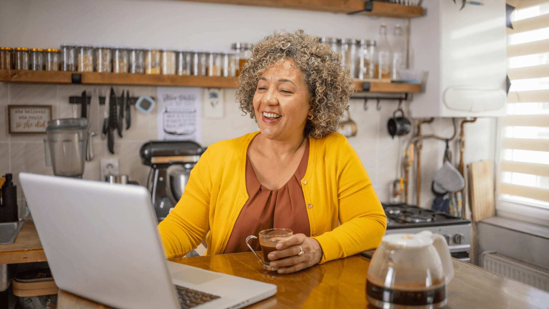 Smiling student at kitchen table networking with mature students studying similar courses and qualifications.