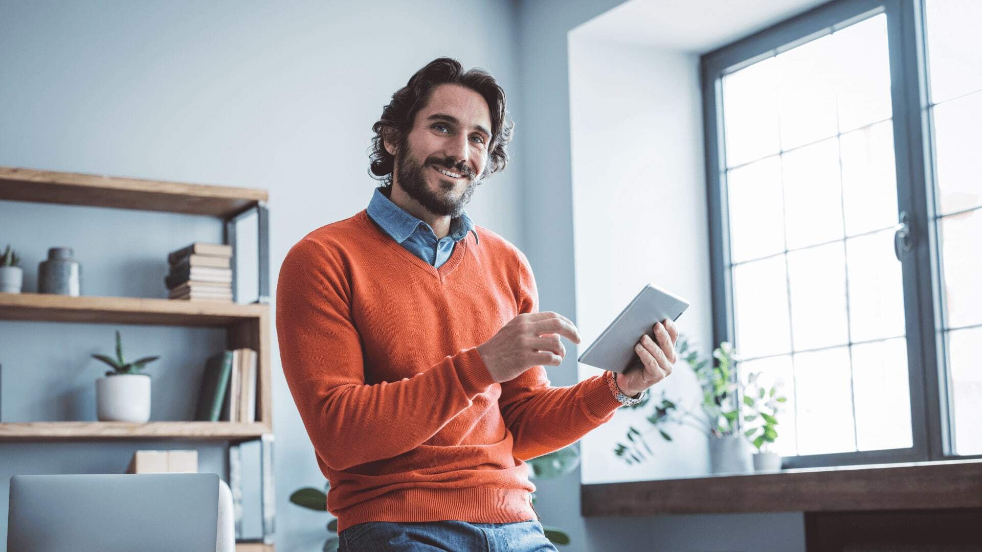 Male professional in orange jumper looks at postgraduate degree reviews by masters students.