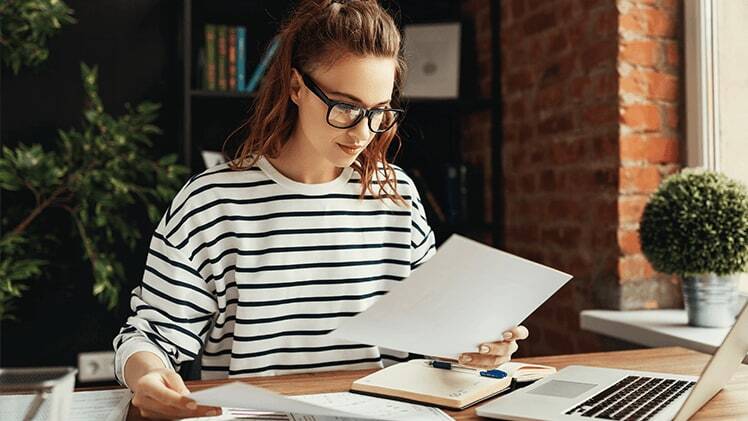 Woman in striped jumper preparing for postgraduate study exams from home