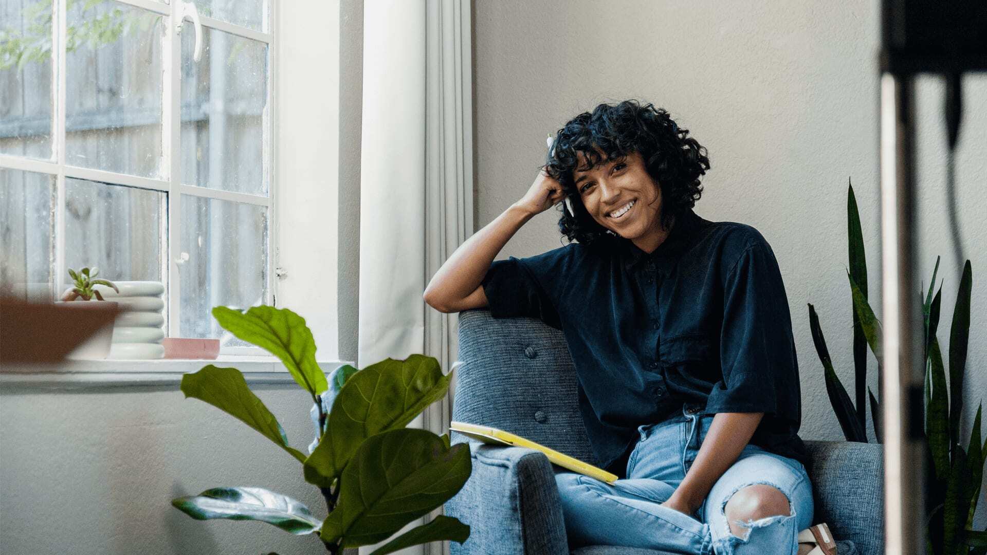 A student sitting on a sofa at home, looking at a laptop with one hand on their head.