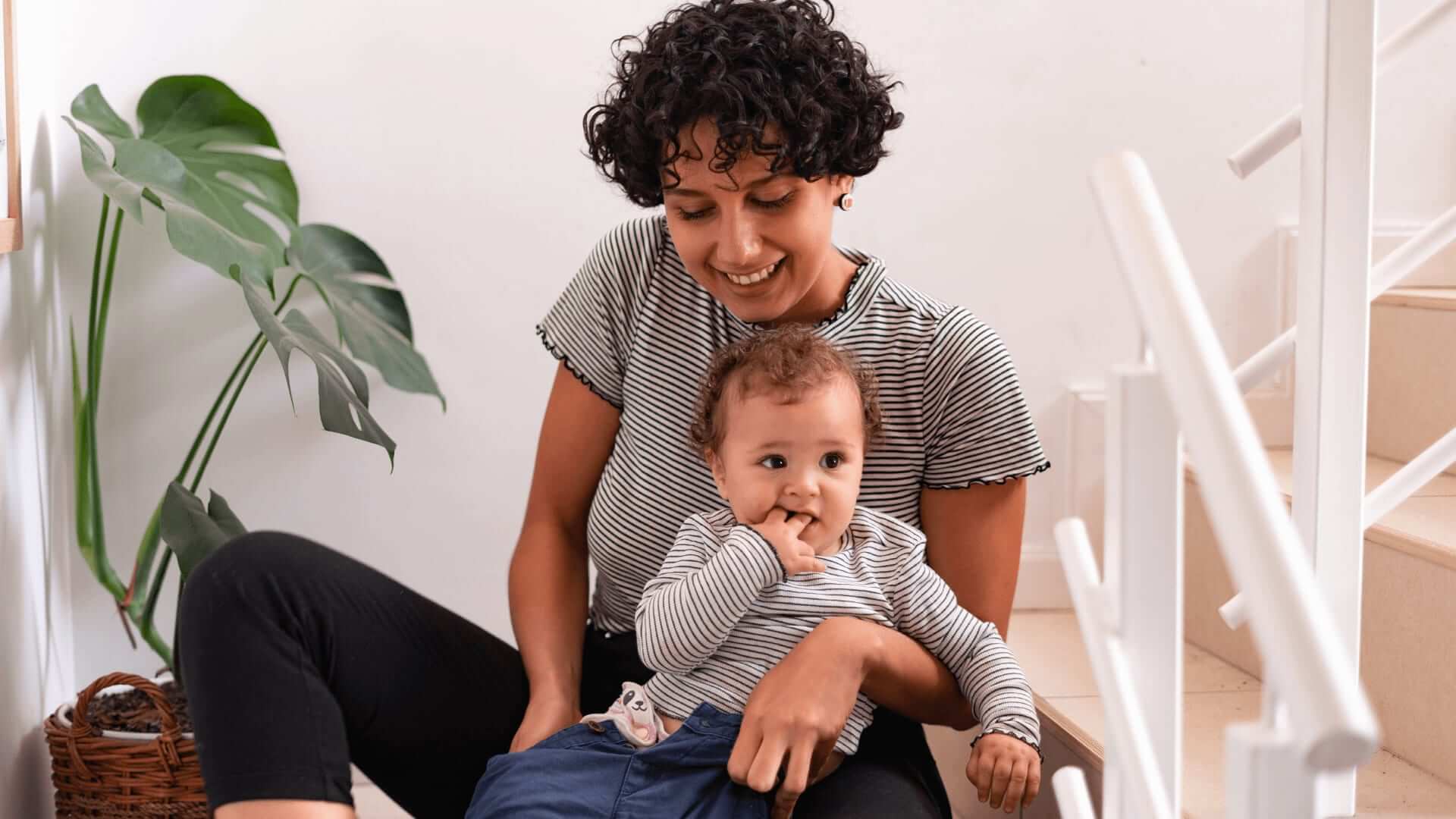 A woman sitting on a sofa with a child, using a laptop.