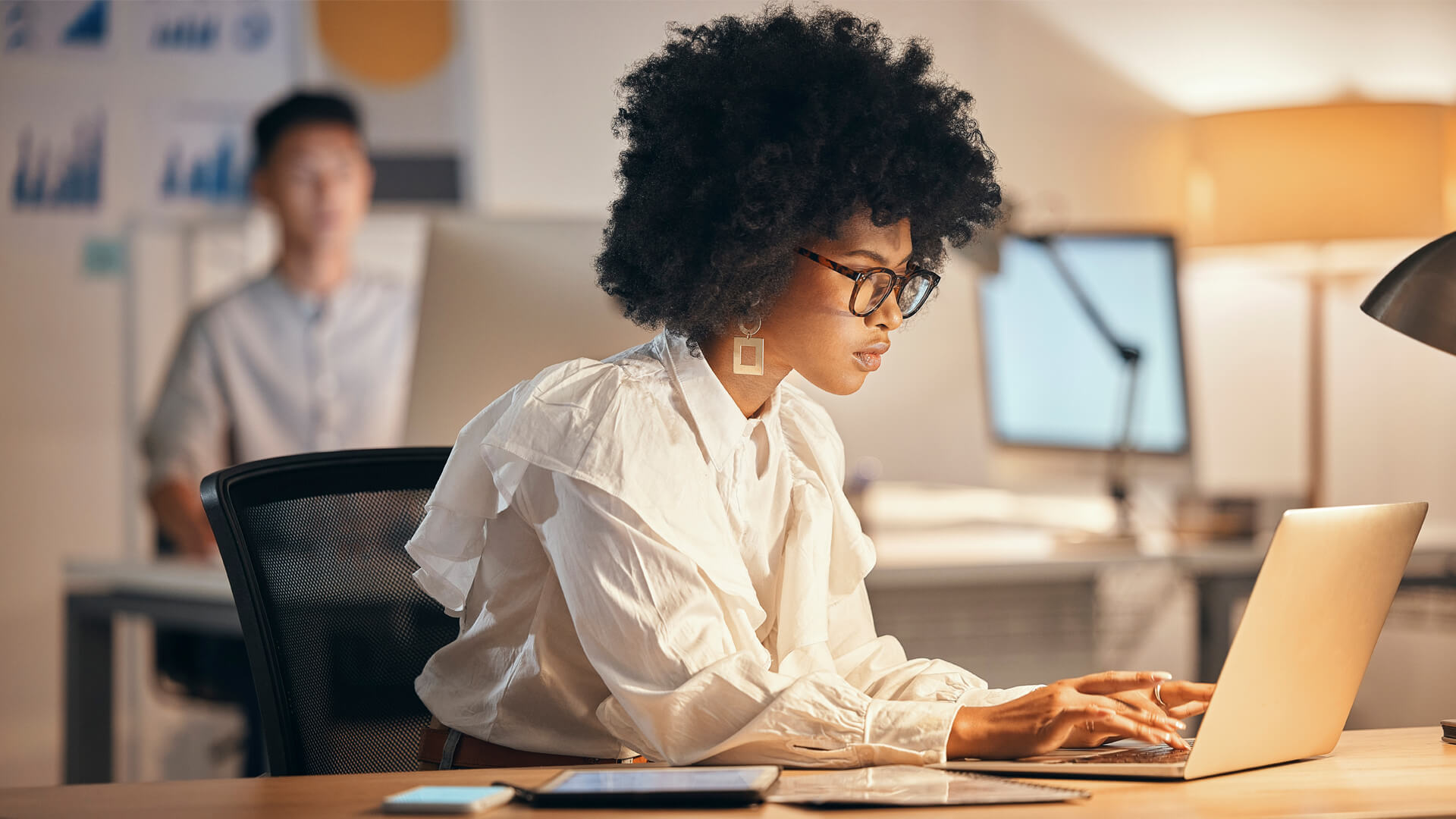 Woman in white shirt works in modern office at laptop.