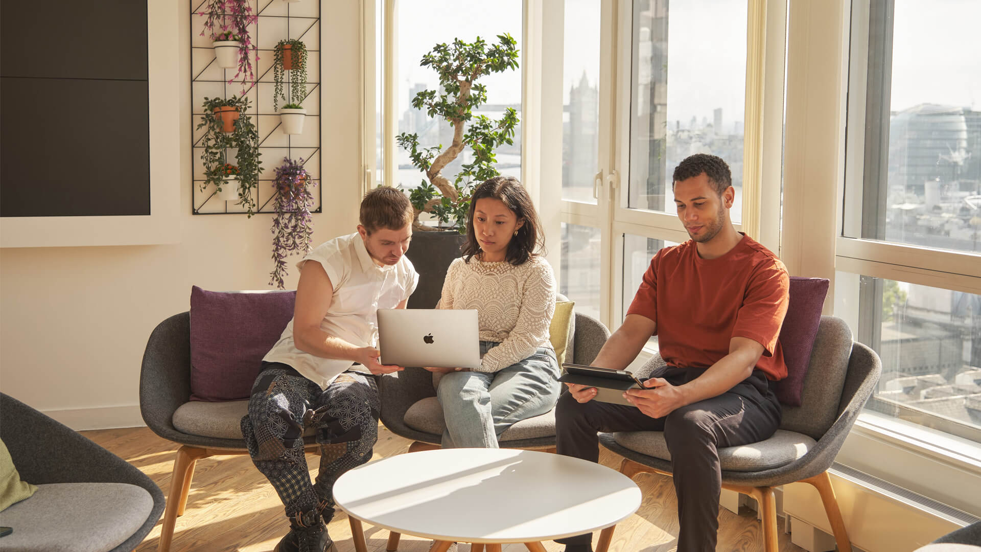 Group of students sat around a laptop at the Walbrook London campus.