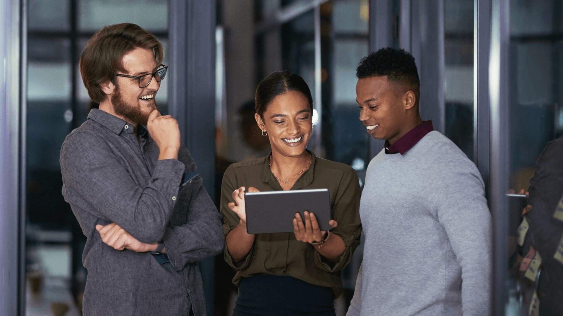 Three people standing together indoors, talking and smiling.