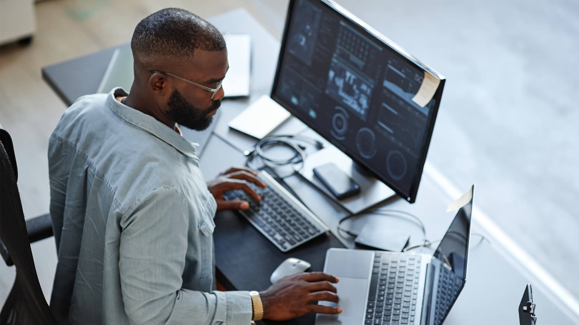 Man photographed from above, sitting at desk in modern grey office.