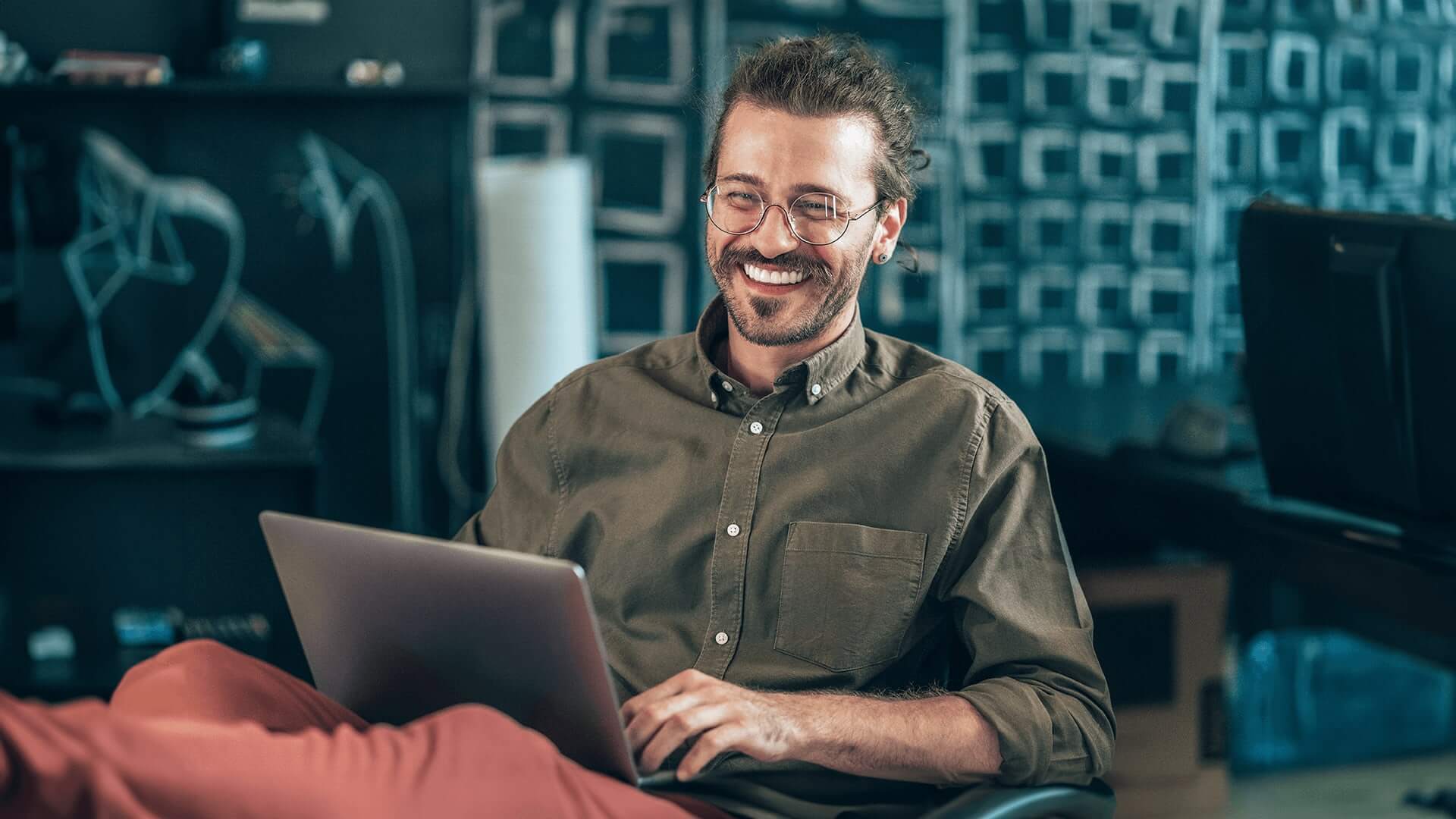 Happy software developer graduate working from a modern office from a laptop.