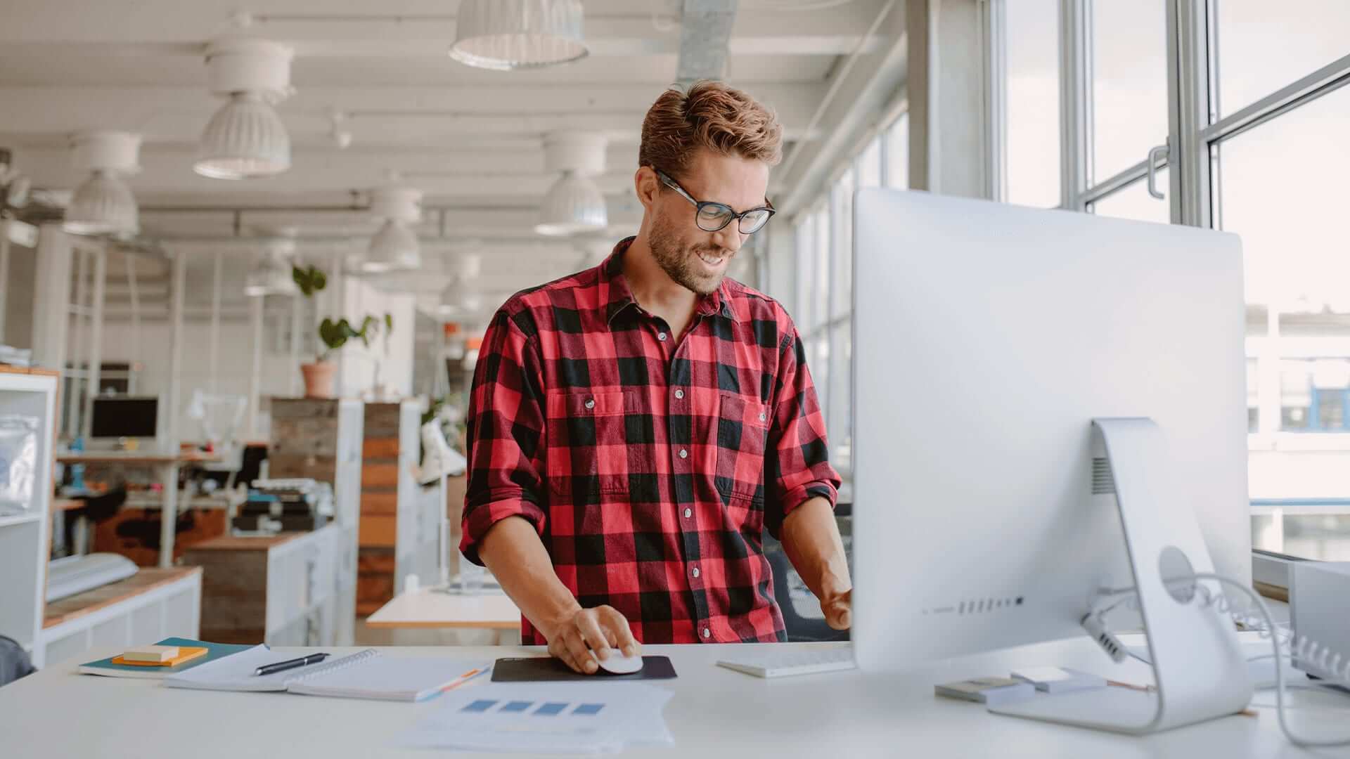 Man in checked shirt working on software design for software systems.