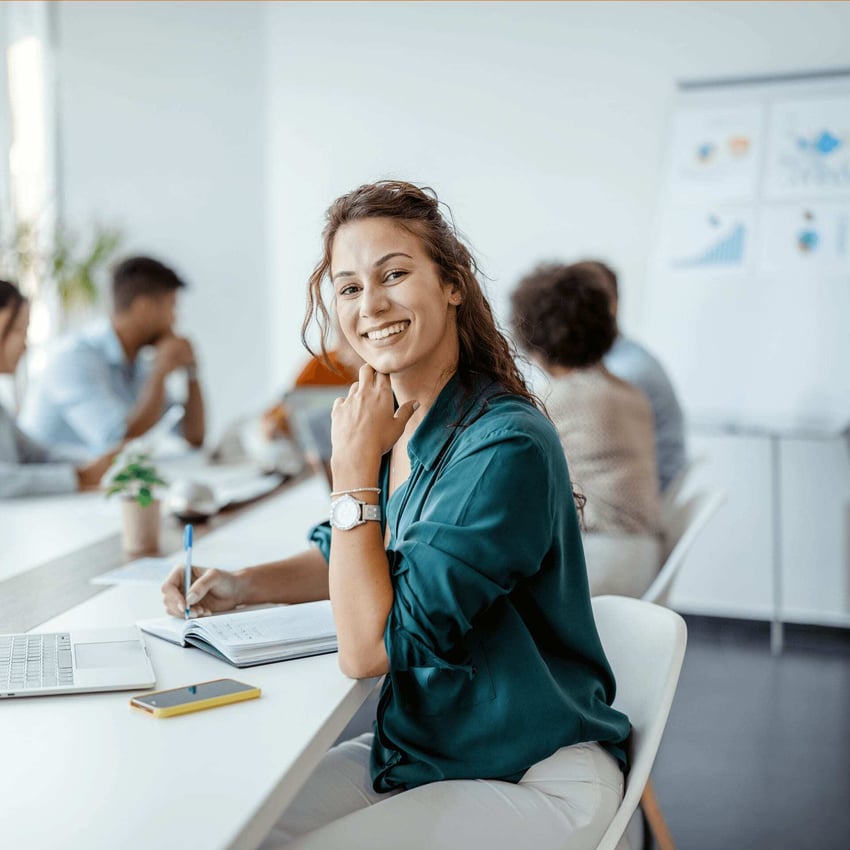 Smiling woman in green shirt analyses consumer behavior for actionable insights to support her organization.