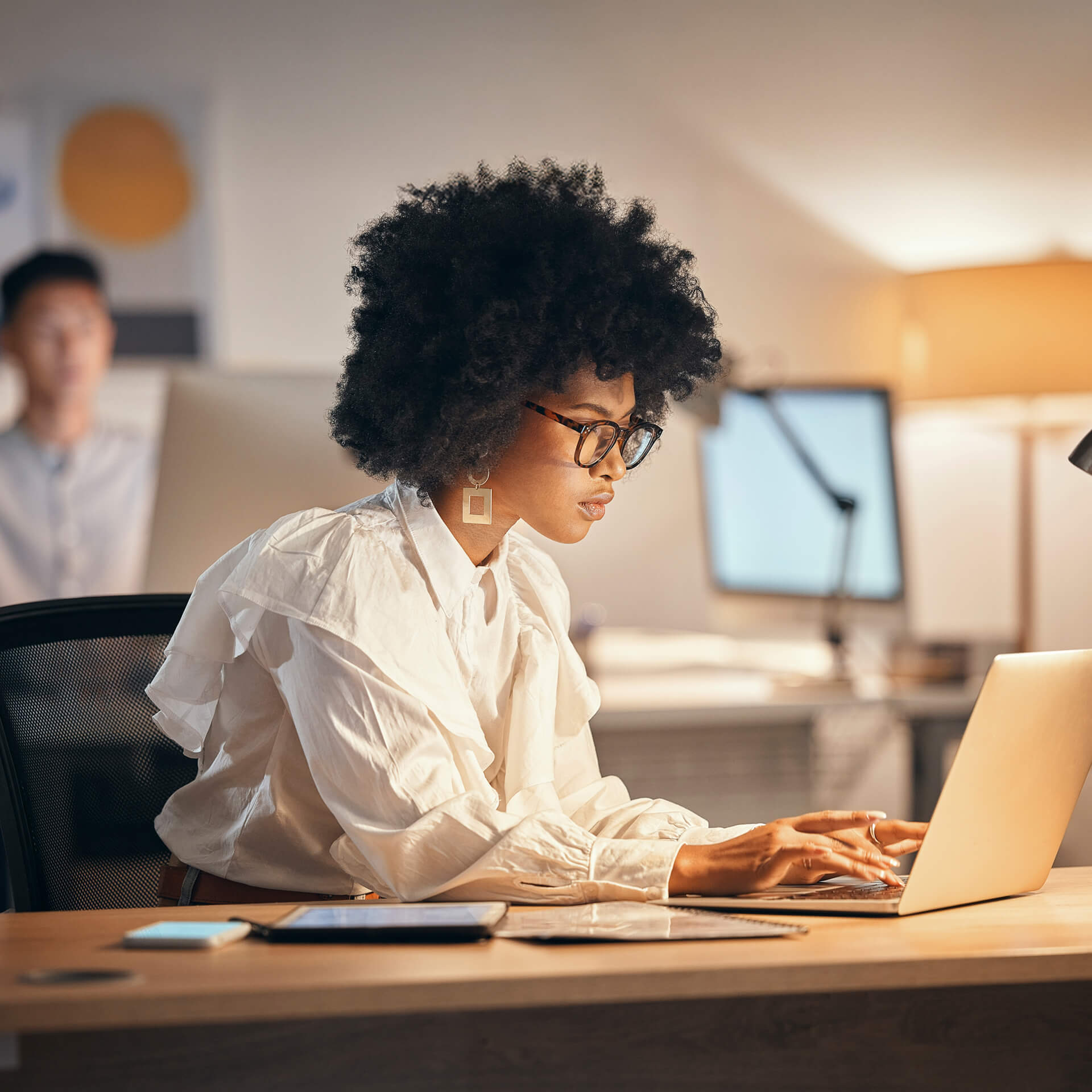 Woman in white shirt working on cyber security project at laptop in office