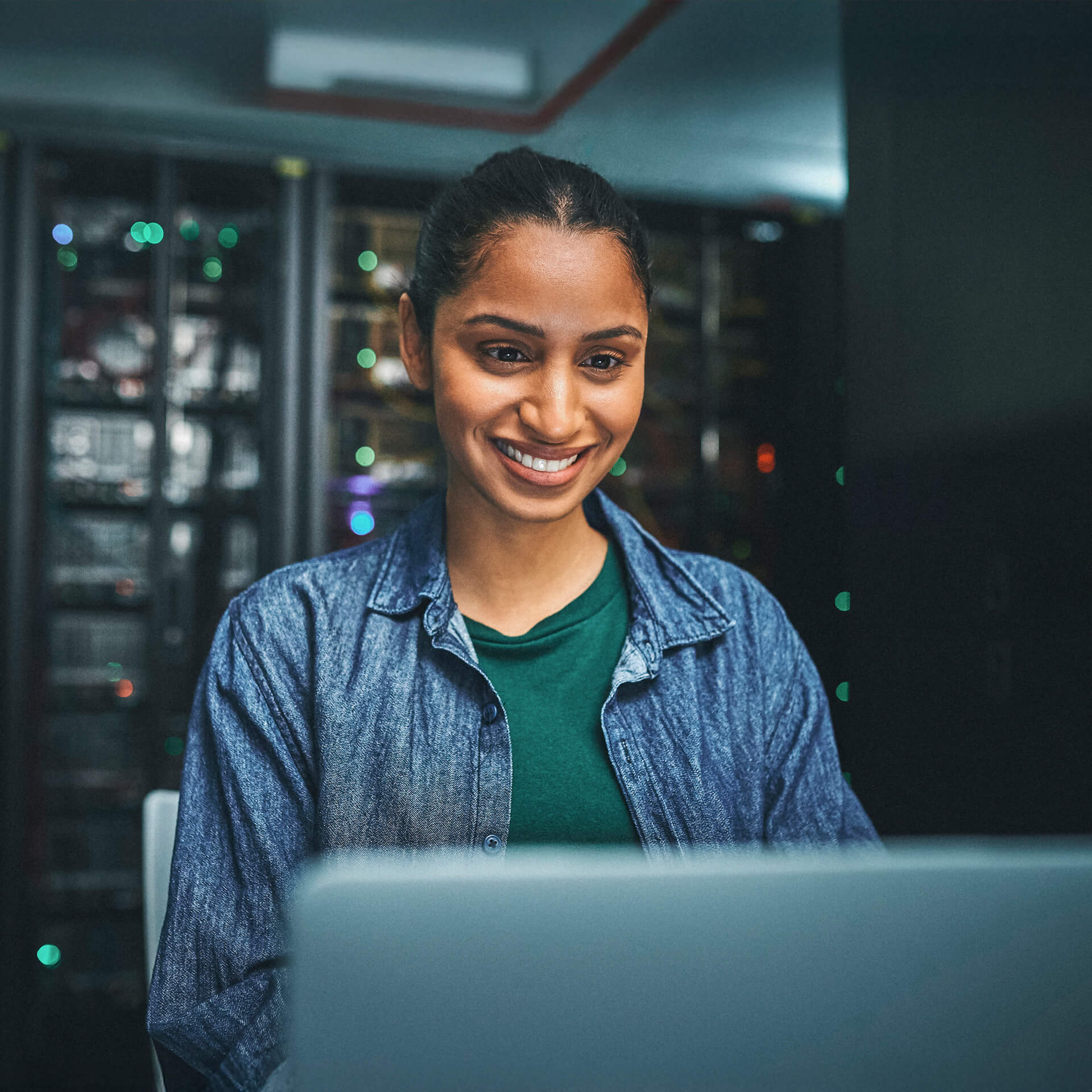 Smiling young professional in denim shirt works in a cyber security office