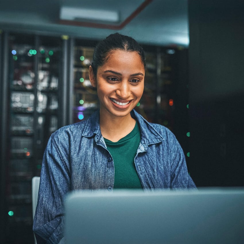 Smiling young professional in denim shirt works in a cyber security office