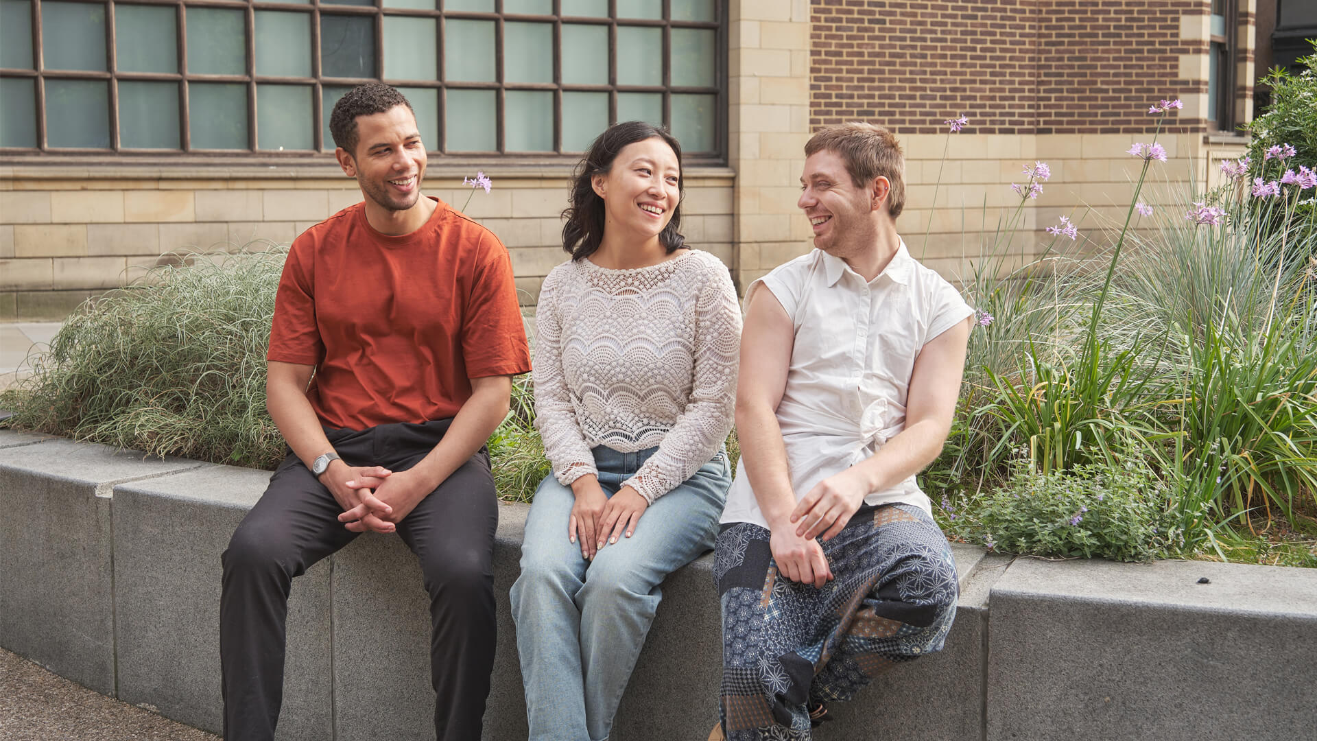 Group of smiling Walbrook students sitting on a wall outside our London campus.