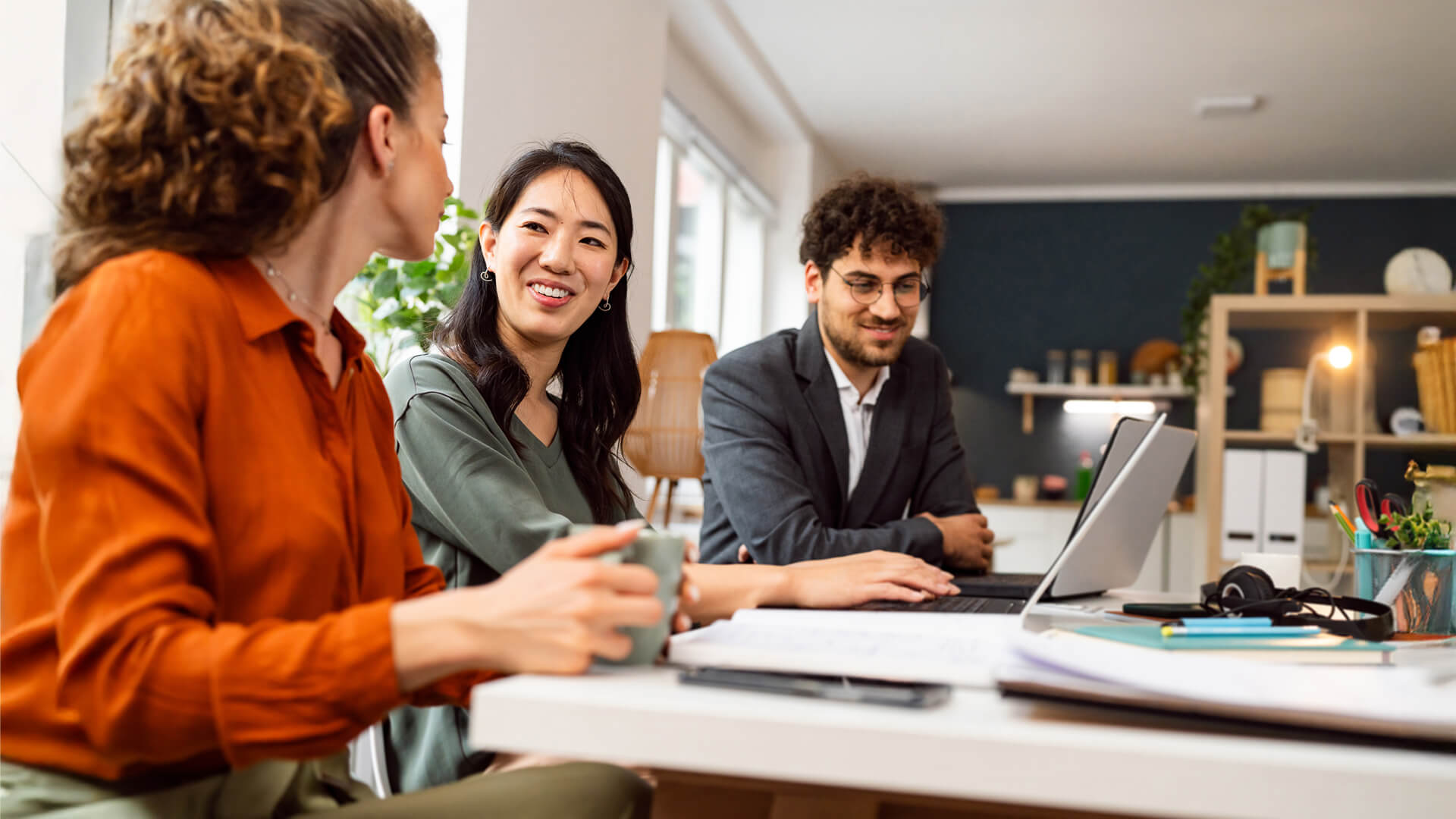 Group of colleagues sit around a laptop in a home office