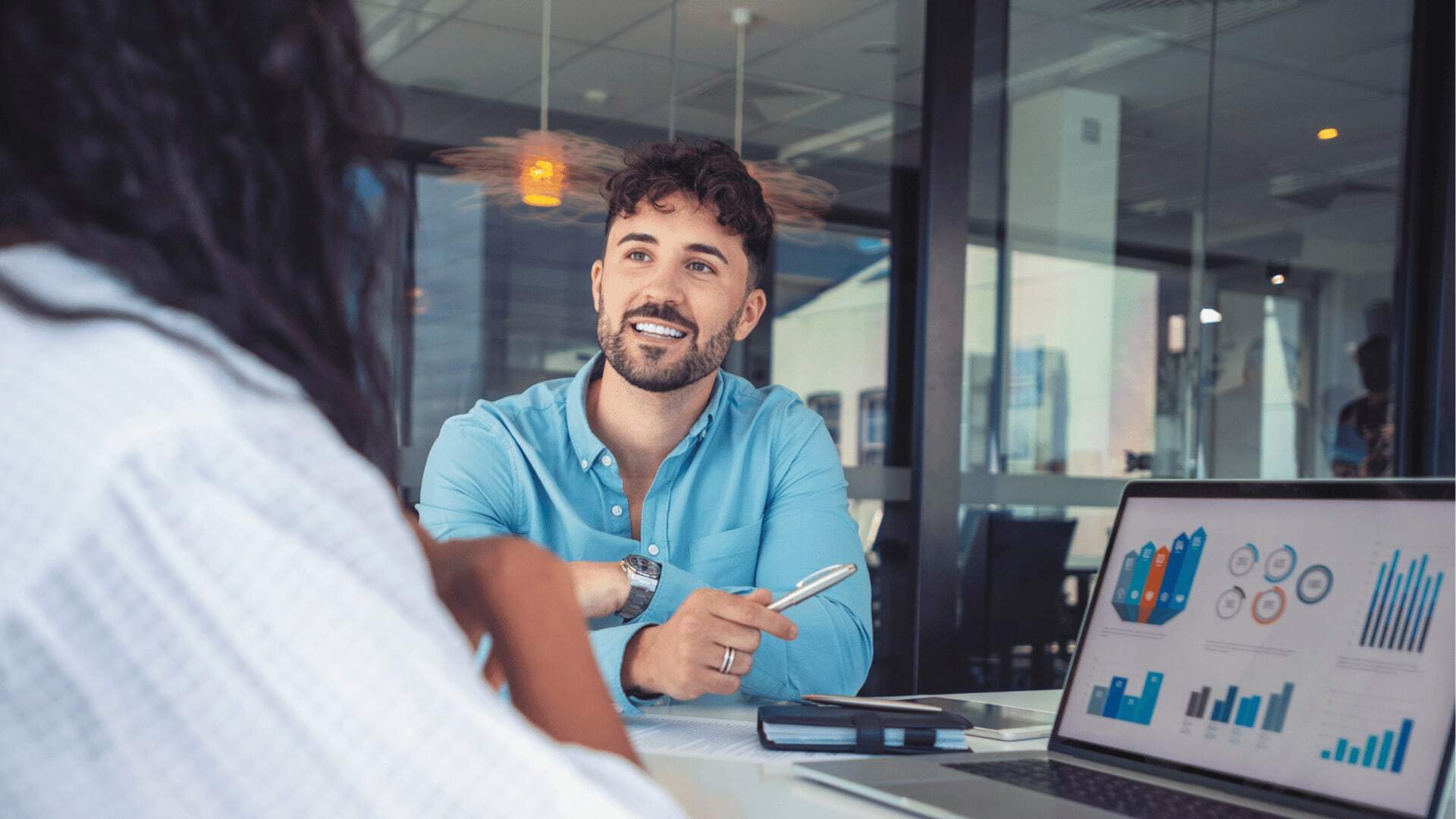 A man speaking on a video call on a laptop while sitting at a desk.