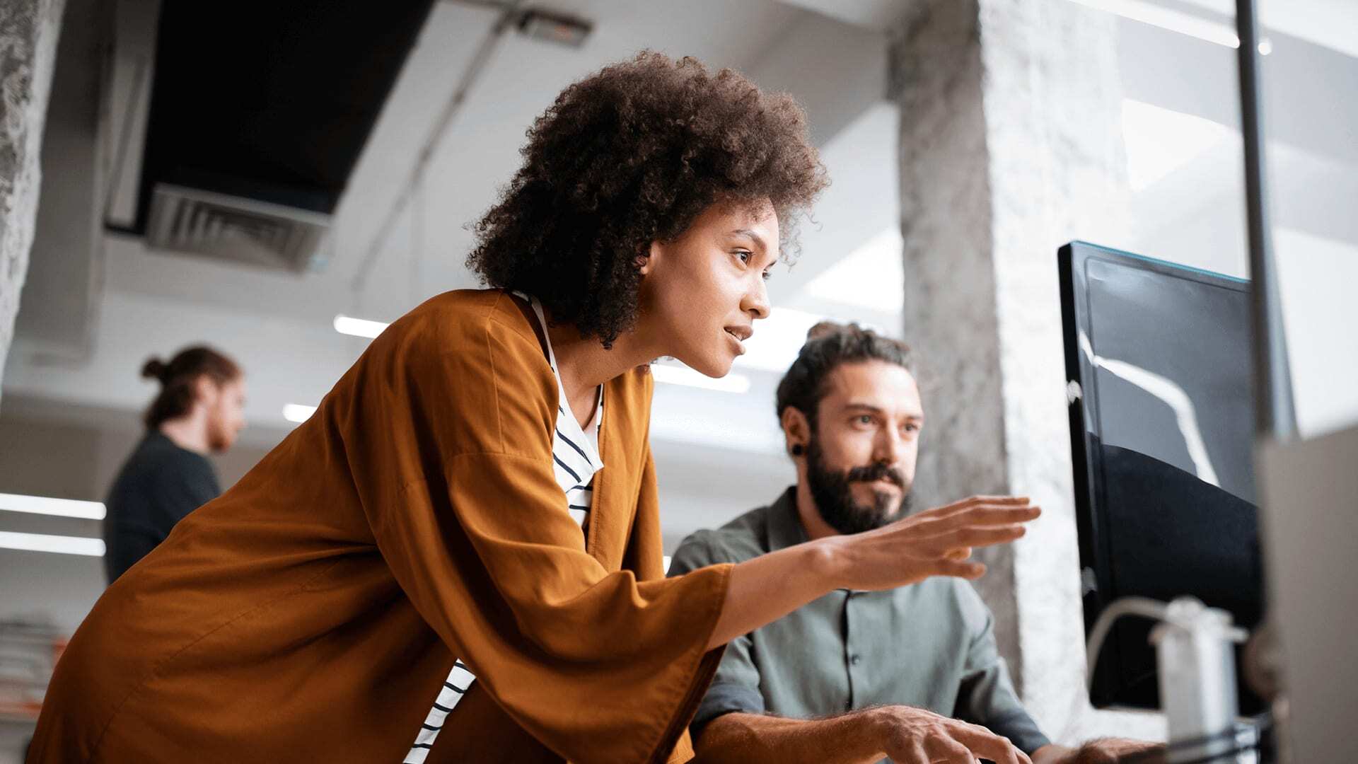 Curly hair woman showing a stakeholder data visualization on desktop computer in organization office.