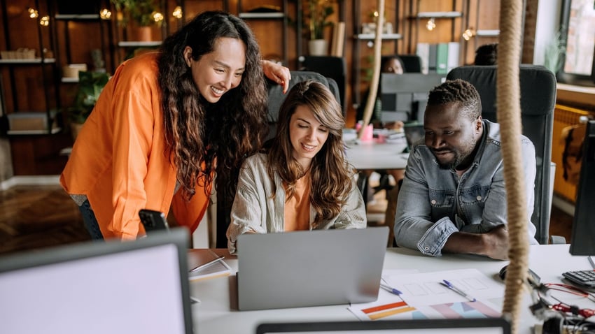 The coworkers discussing over a laptop screen