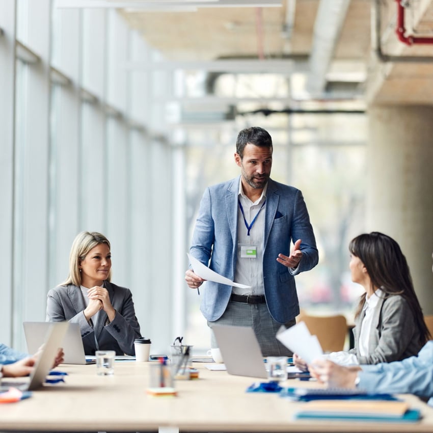 Man standing up and talking during a meeting with colleagues