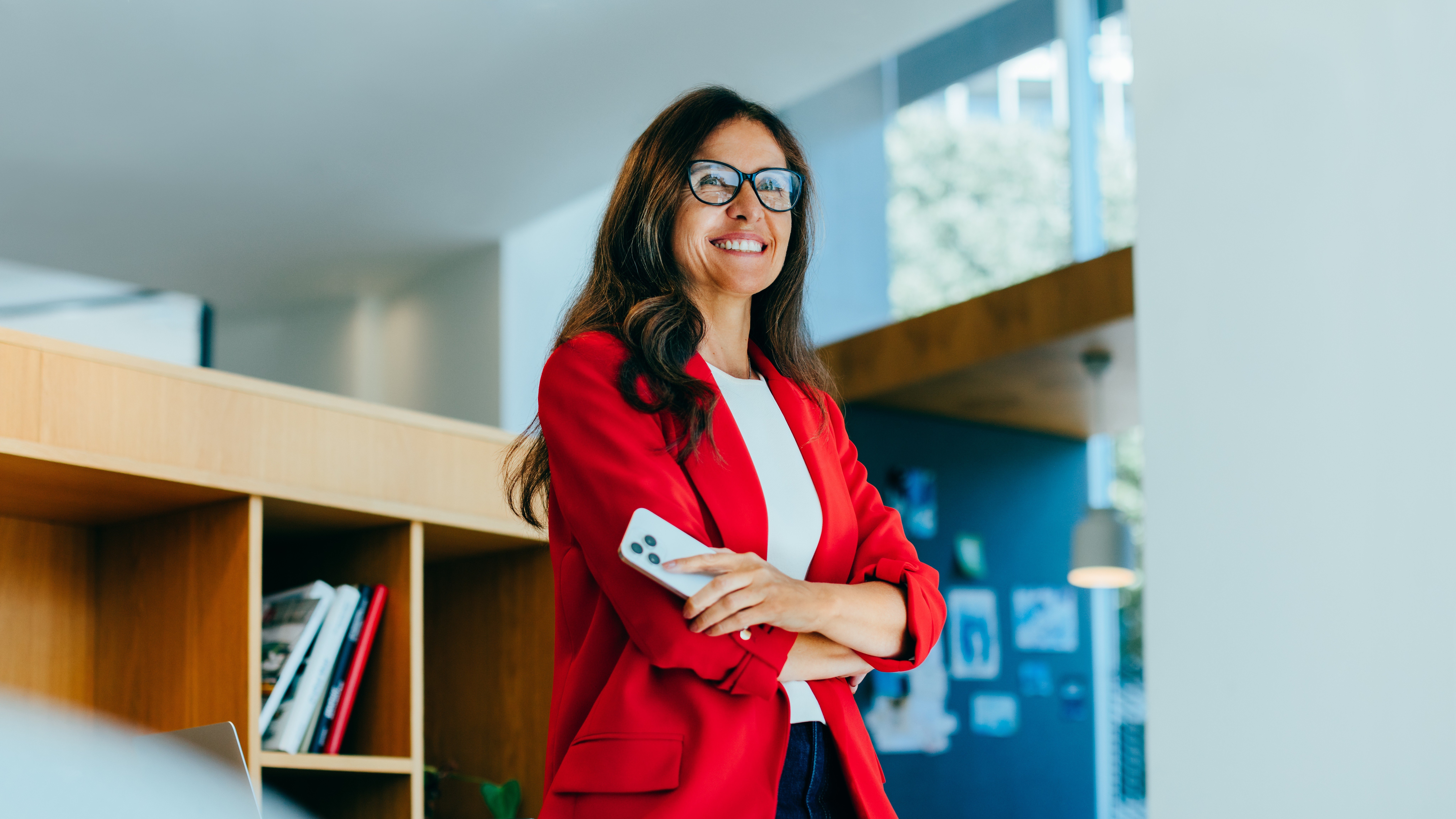 Woman smiling and holding a phone in an office environment