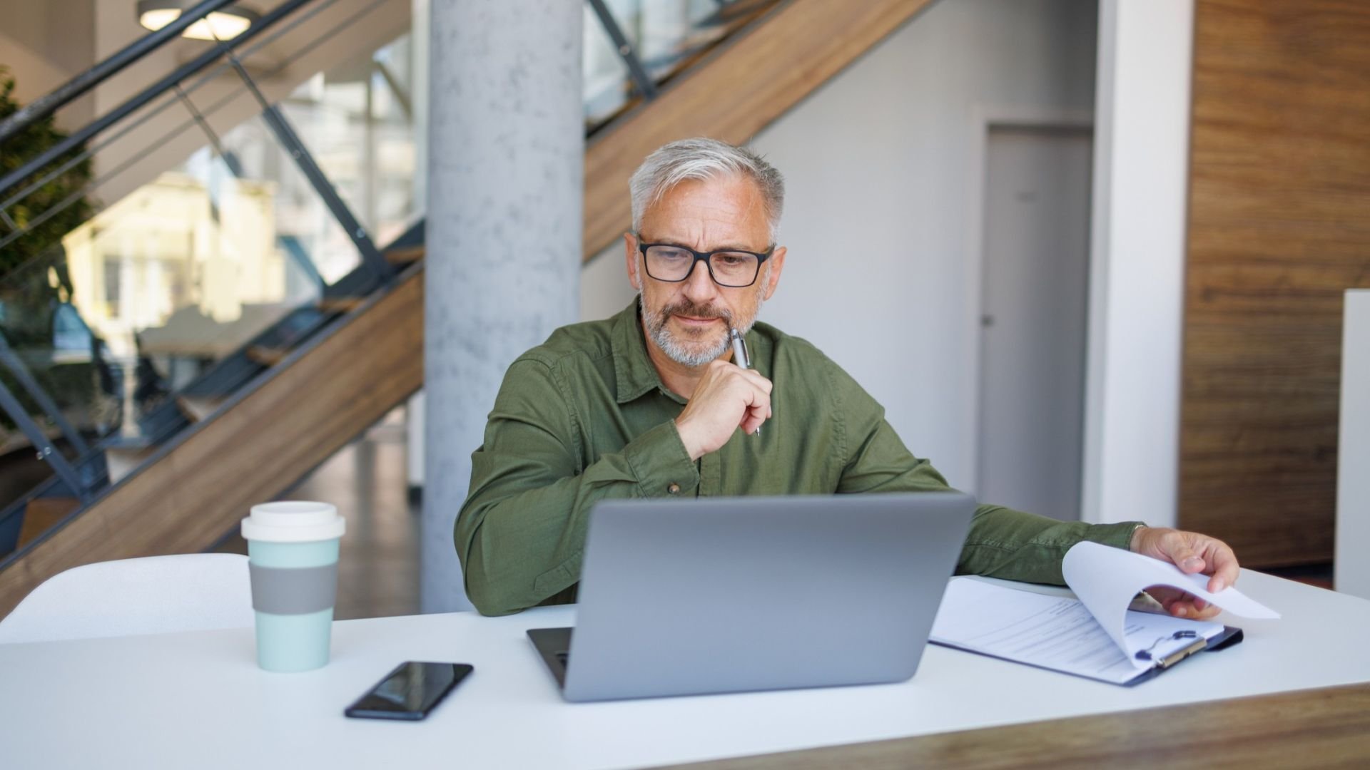 Older man working on a notepad and looking at his laptop