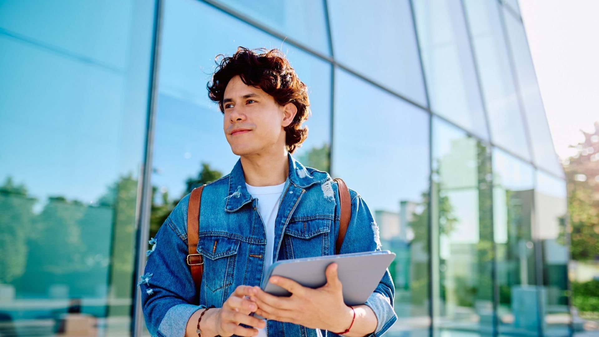 Student standing outside of a building holding their laptop