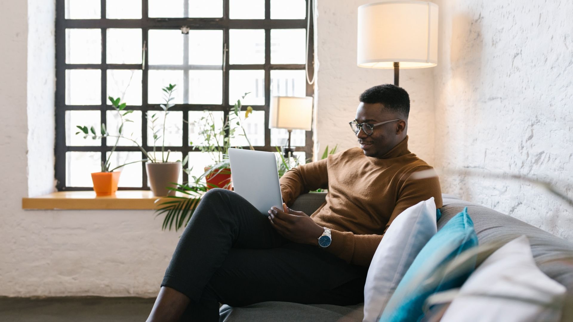 Man sitting of a sofa in home setting, using his laptop
