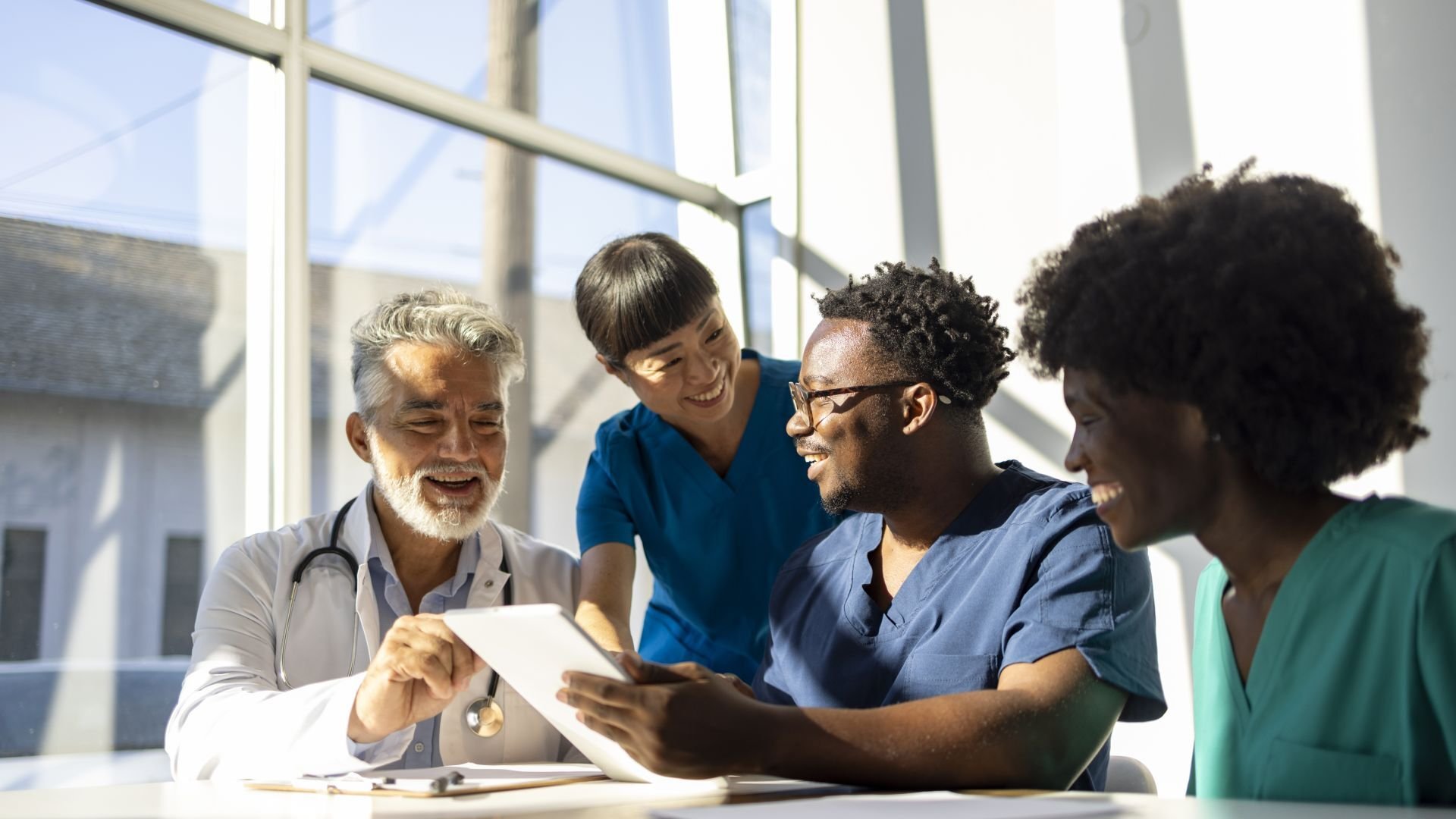 A doctor and various healthcare workers talking together over a tablet