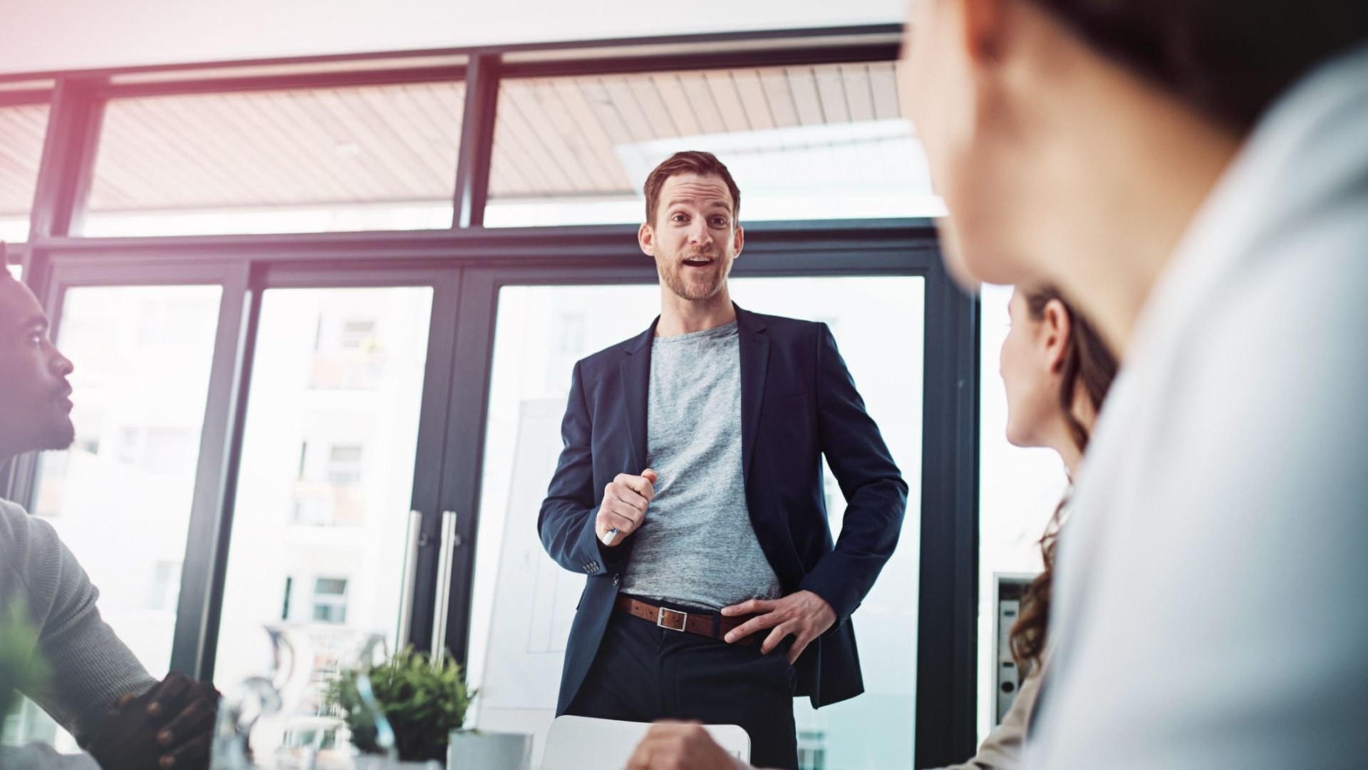 Man leading a meeting and speaking in front of coworkers