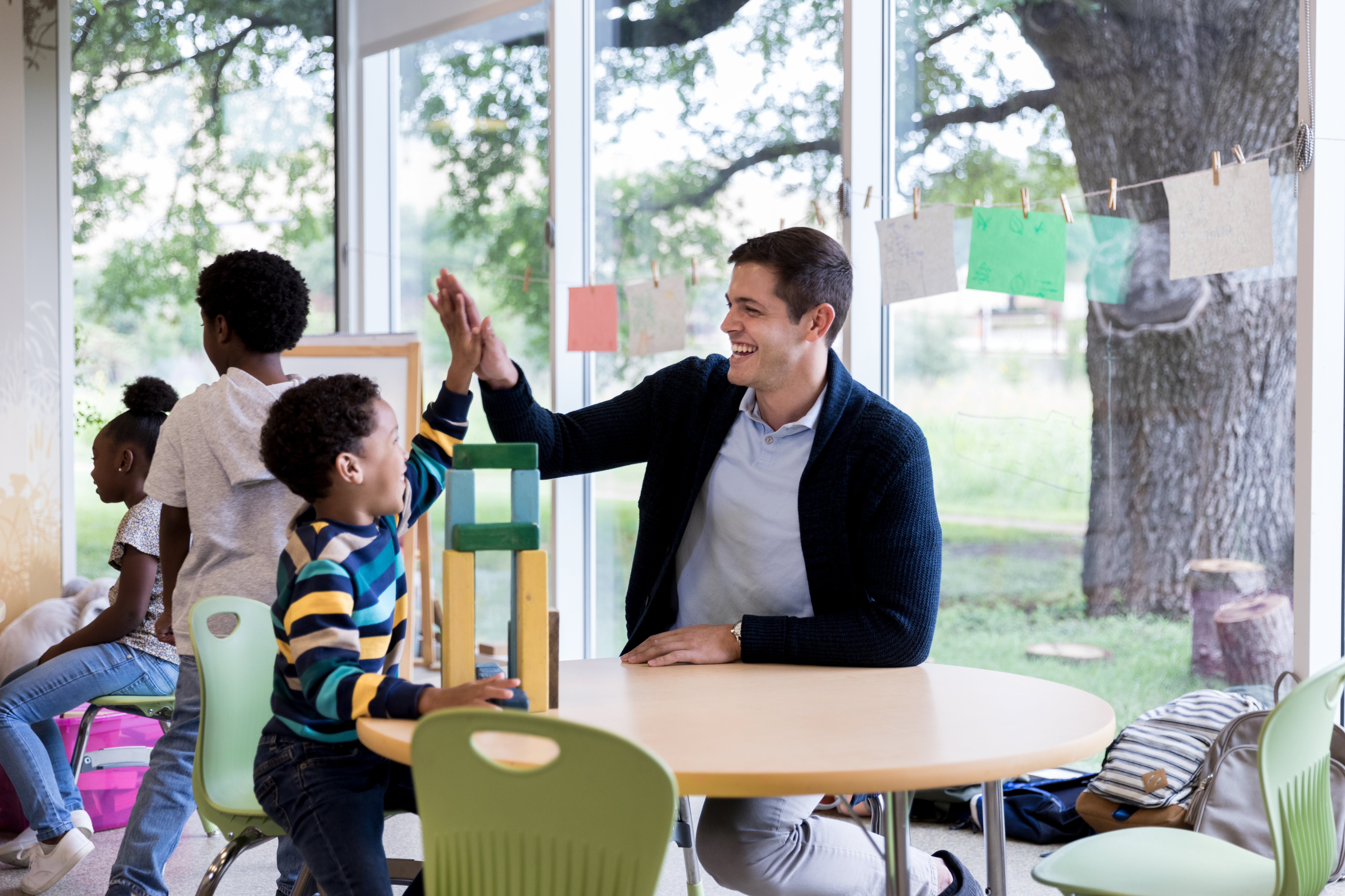 Male teaching assistance high fiving with a child