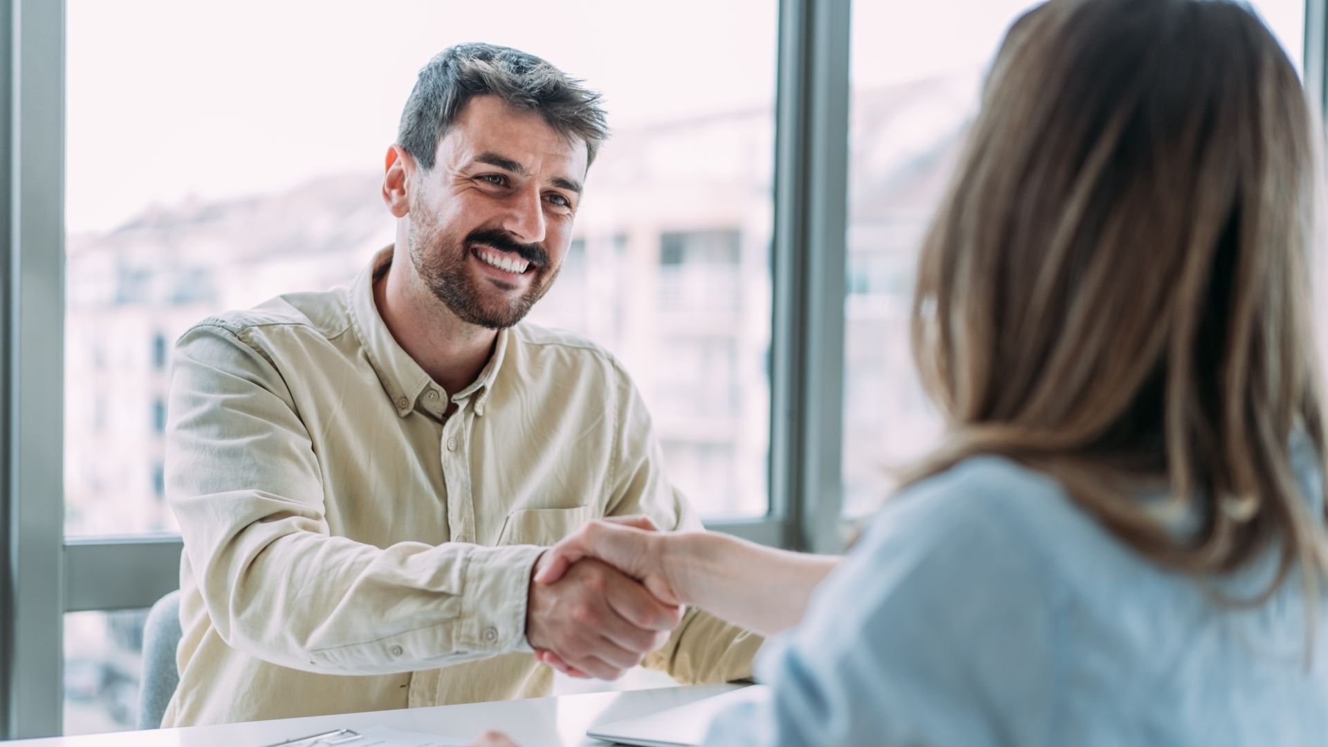 Man and woman shaking hands over a desk