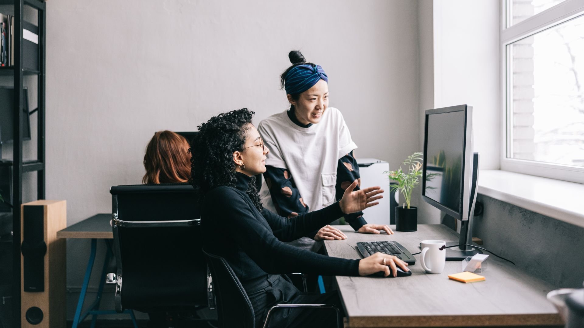 Two coworkers discussing something on a computer screen together