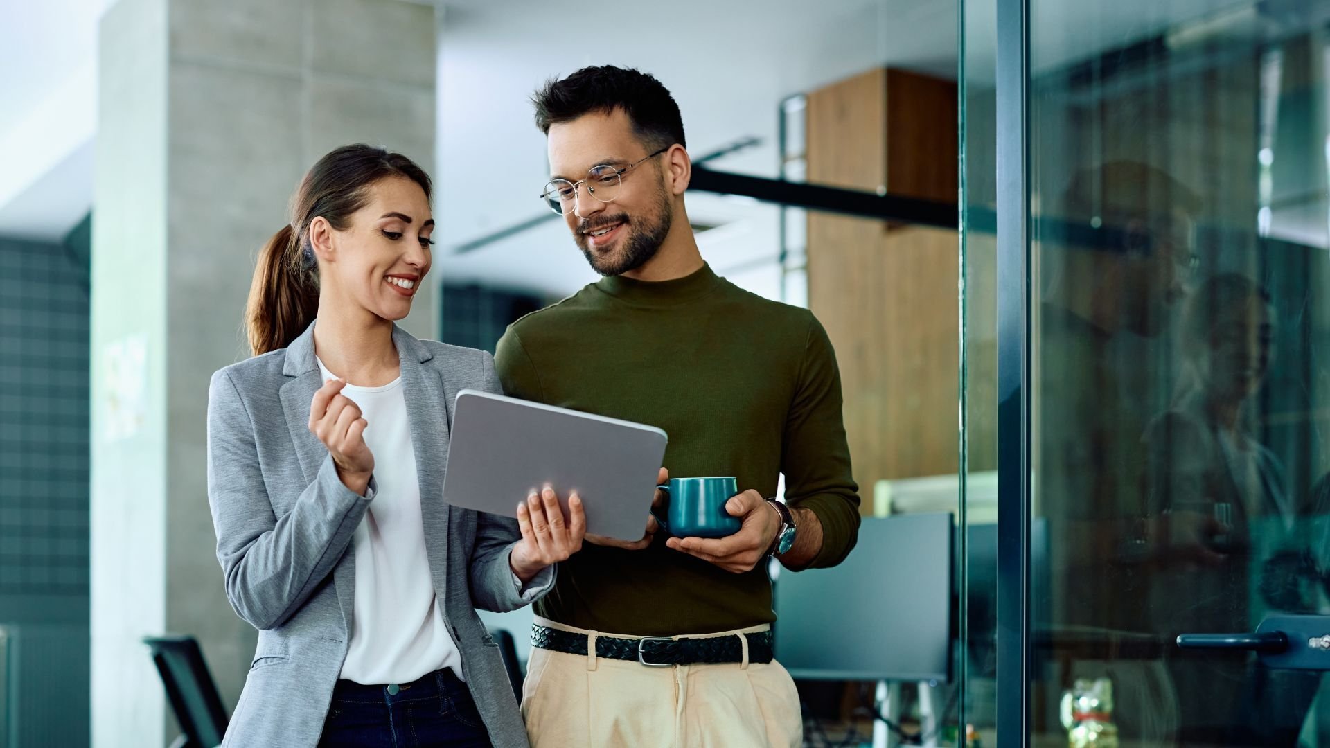 Two coworkers walking and discussing over a tablet