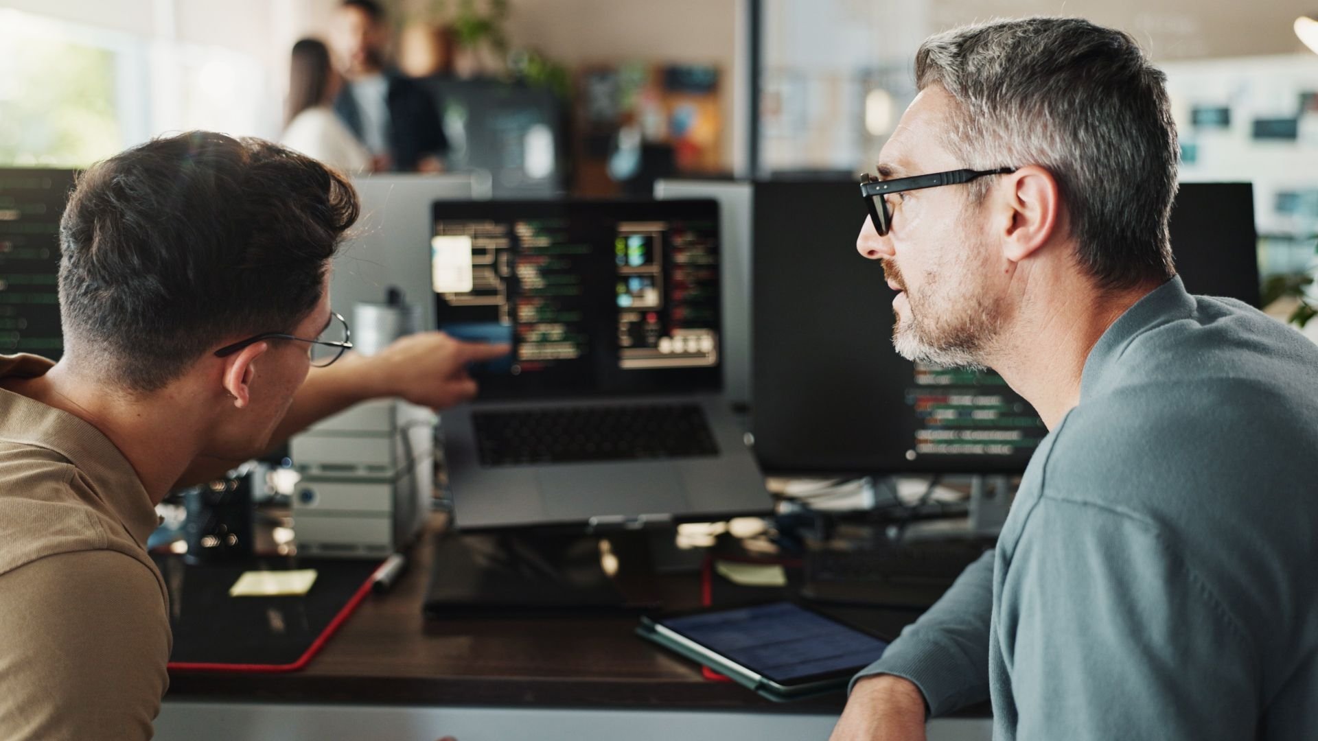 Two men discussing what is on a laptop screen