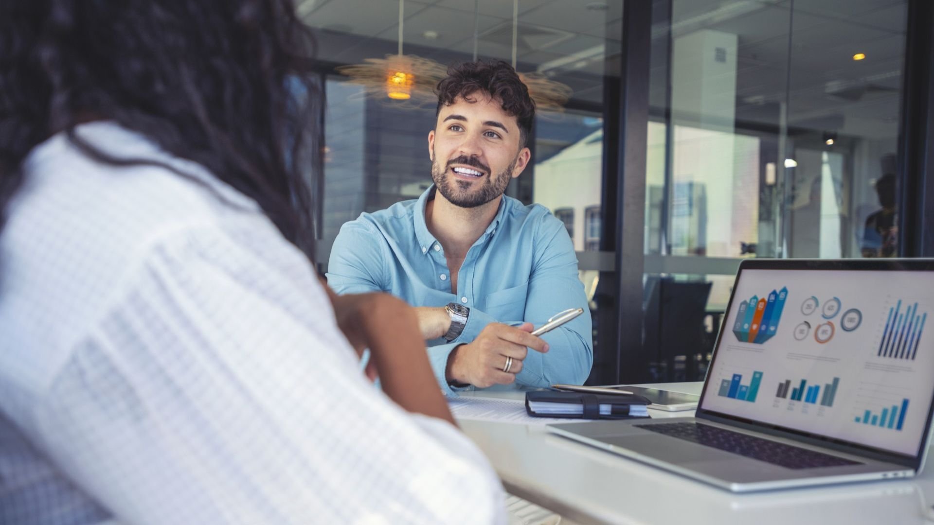 Man discussing with another with laptop in the for ground