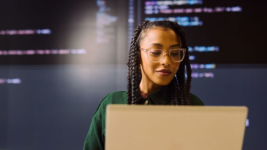 Woman using laptop with larger screen in the background