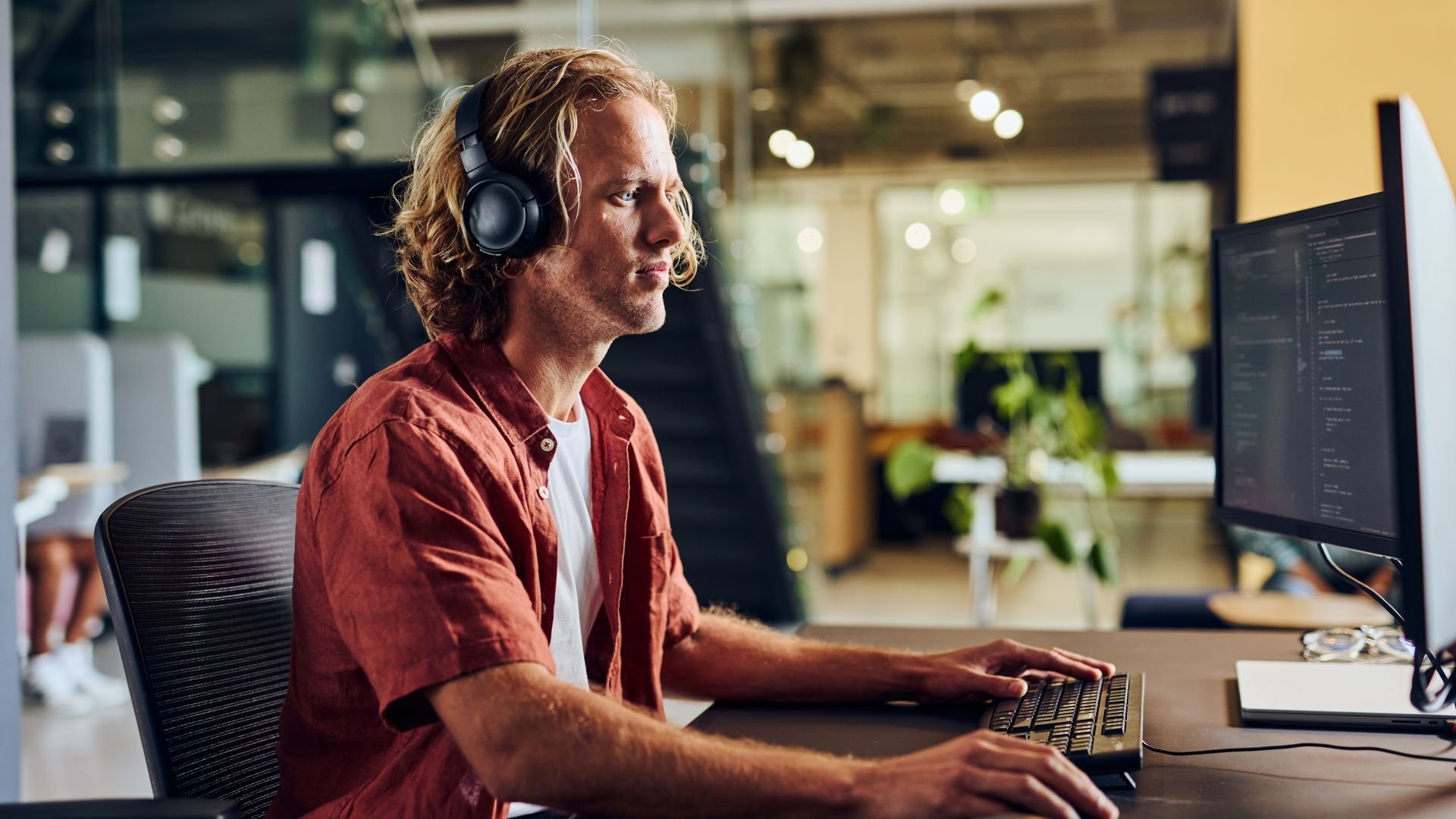 Man using a PC and headphones in an office setting