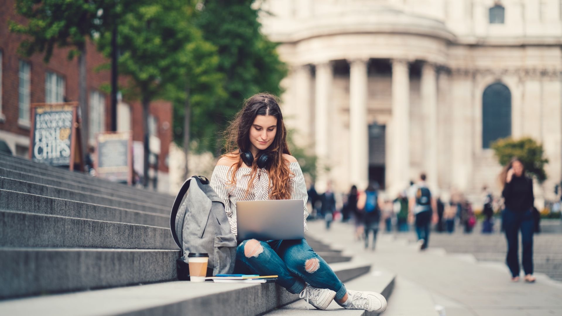 Woman sitting on a step in city using her laptop