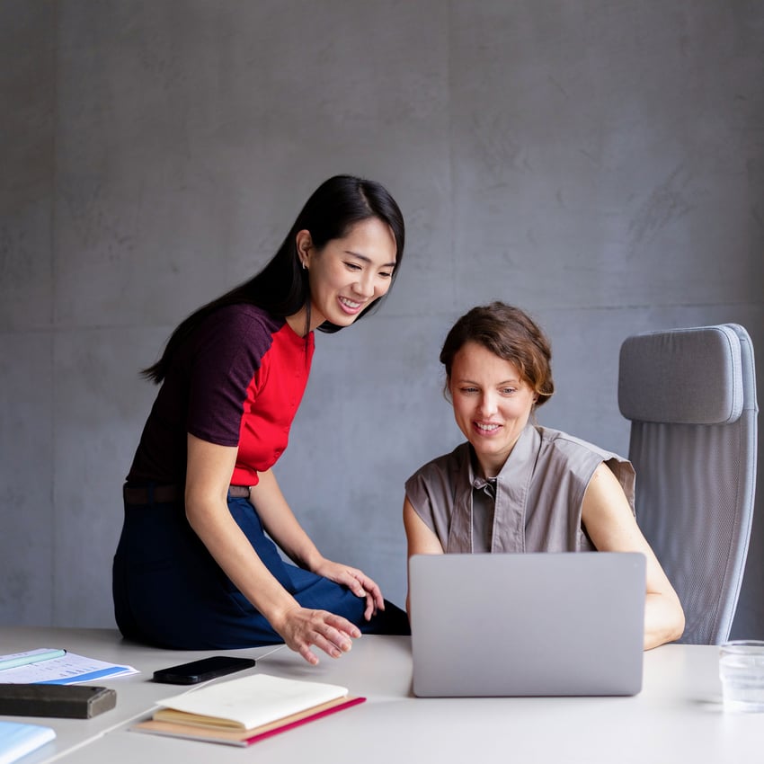 Two coworkers discussing over a laptop