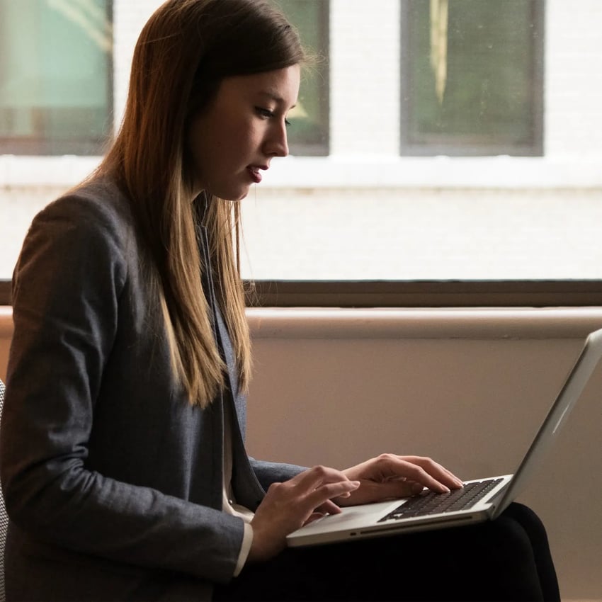 Young woman sitting with a laptop on her lap.
