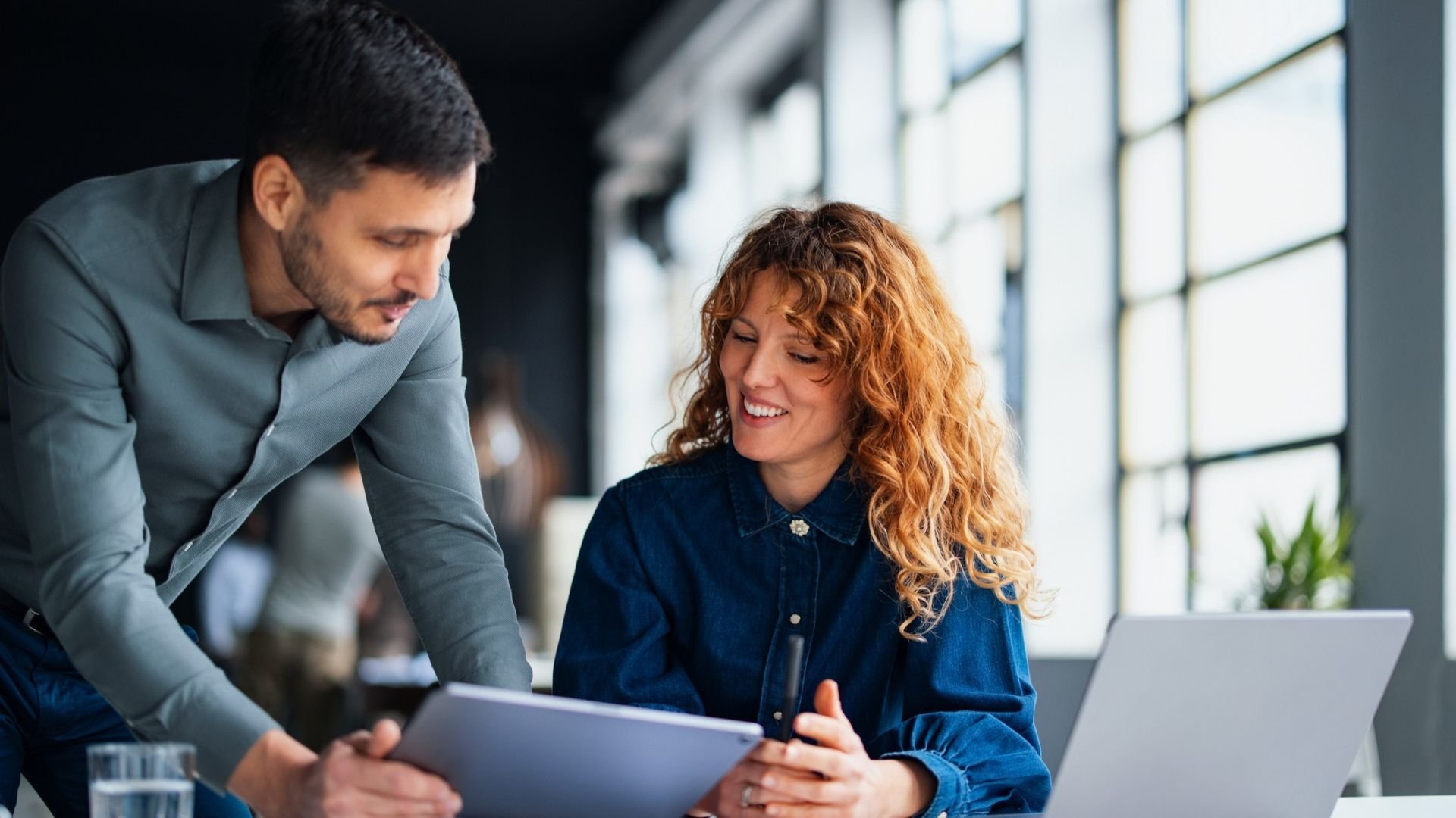 Man and a woman discussing over a laptop in a work environment