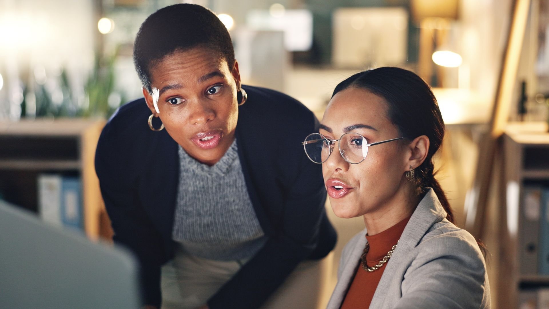 Two women discussing something on a computer screen