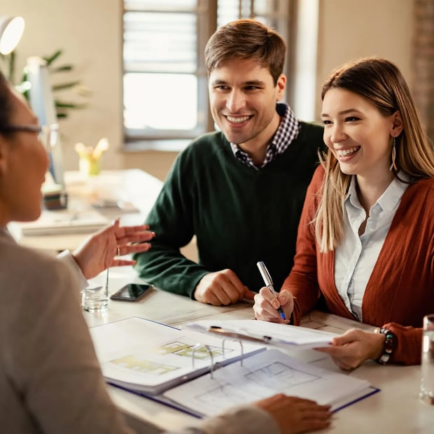 A man and a woman talking to an advisor and signing a document.