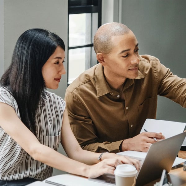 A man and a woman working on their laptops.