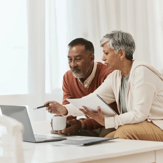 Two old people sitting and looking at the computer.