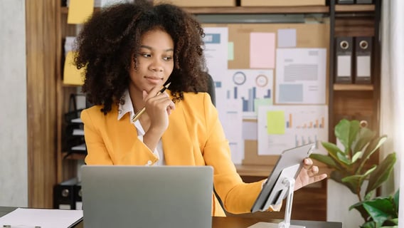 A woman sitting at her desk and looking at her ipad.