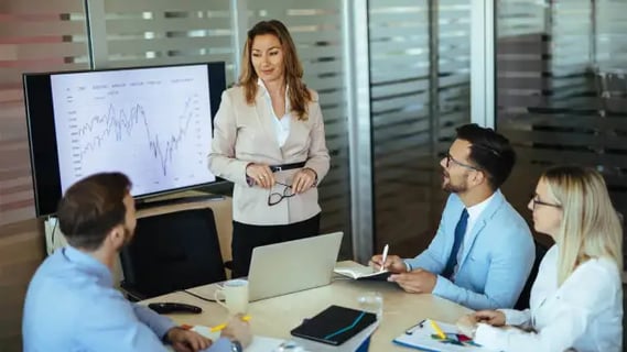 MBA Finance graduate presents data trends during a team discussion, encouraging strategic decision-making.